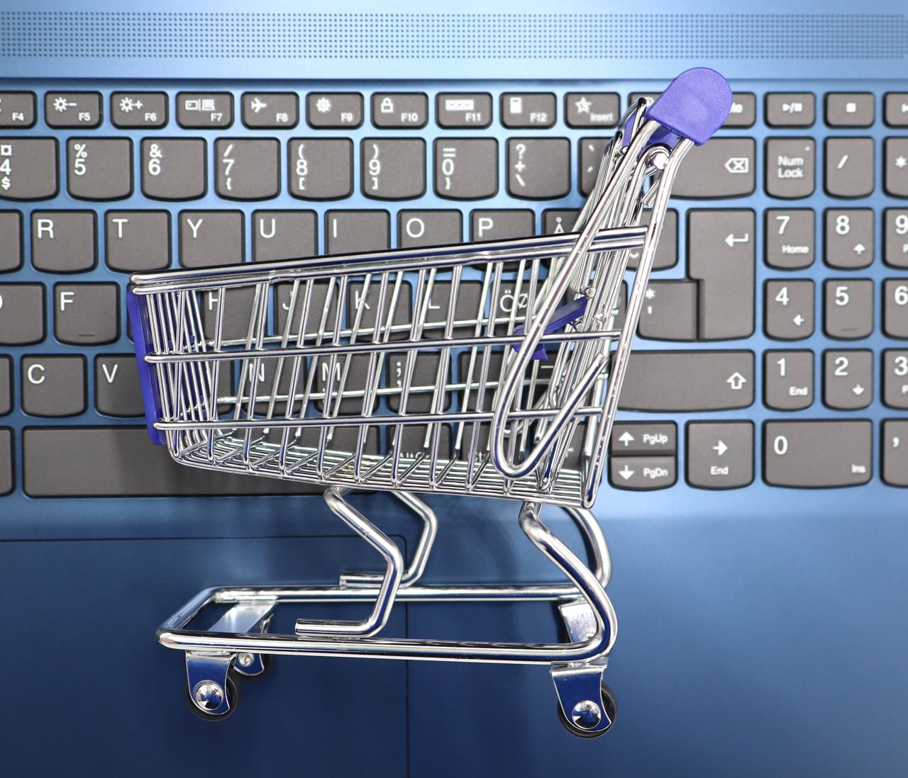 Un panier d’achat miniature posé sur le clavier d’un ordinateur portable, symbolisant les achats en ligne et le commerce électronique.